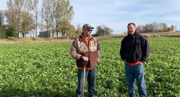 Two men standing in farm field