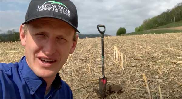 Man talking to camera in farm field with shovel