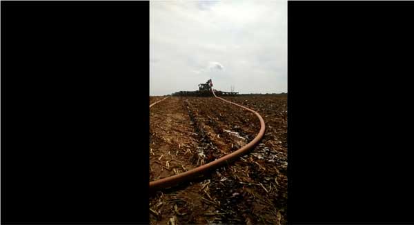 Long hose attached to tractor in farm field