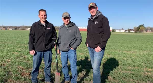 Three men standing in farm field