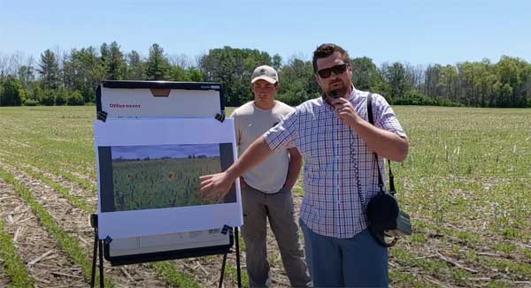 Two men standing in farm field with flip chart