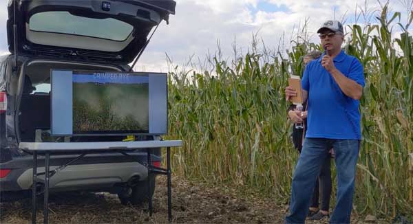 Farmer standing in corn field talking into a microphone