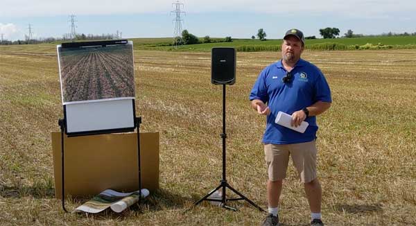 Man standing in farm field with flip chart