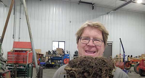 Farmer holding clump of soil inside of equipment barn