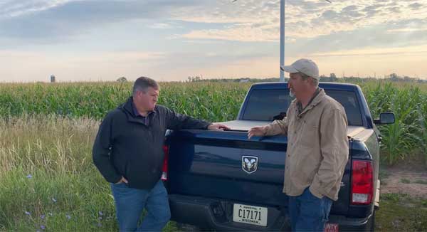 Two men standing at truck tailgate talking