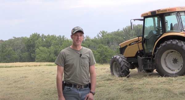 Man standing in farm field with tractor