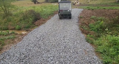 Field buggy on a stream crossing within a pasture with goats in the background.